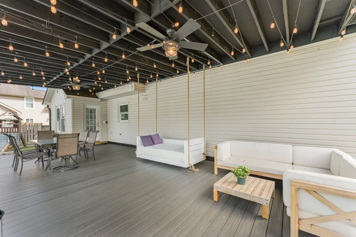 This image showcases an outdoor seating area with a swing seat, a table with chairs, and hanging light fixtures, set in a cozy atmosphere ideal for relaxing or enjoying meals outside. The setting is social and inviting, perfect for entertaining guests or unwinding after exploring local dining options.