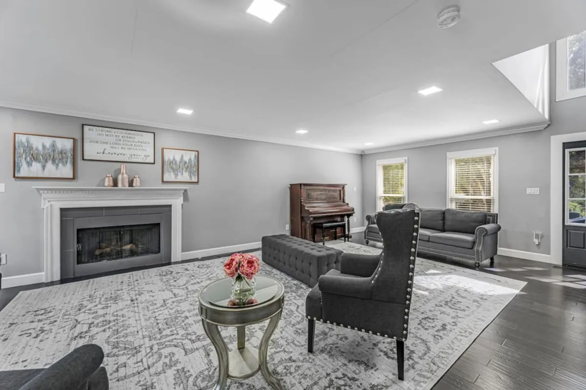 A sophisticated living room features a piano near a fireplace, surrounded by comfortable seating and artful décor, inviting both music performances and relaxed gatherings. The overall mood is welcoming—perfect for returning from Knoxville’s vibrant arts scene and continuing the musical inspiration at home.